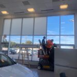 Sunray Window Films technicians installing Solyx Snow White Light Diffuser film inside Ken Ganley Volkswagen showroom.